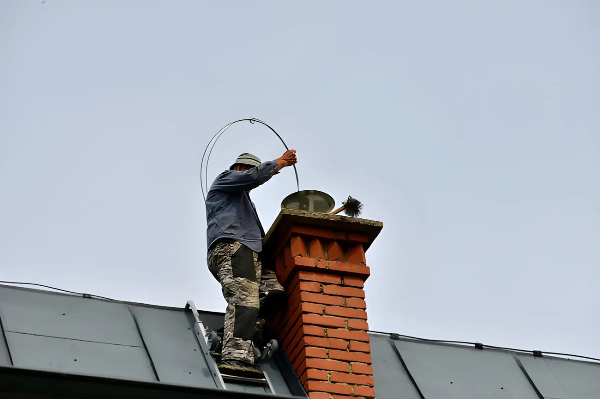 Roofer working at the top of a brick chimney stack