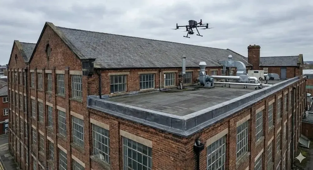 Drone flying over a flat-roofed brick building during a roof survey