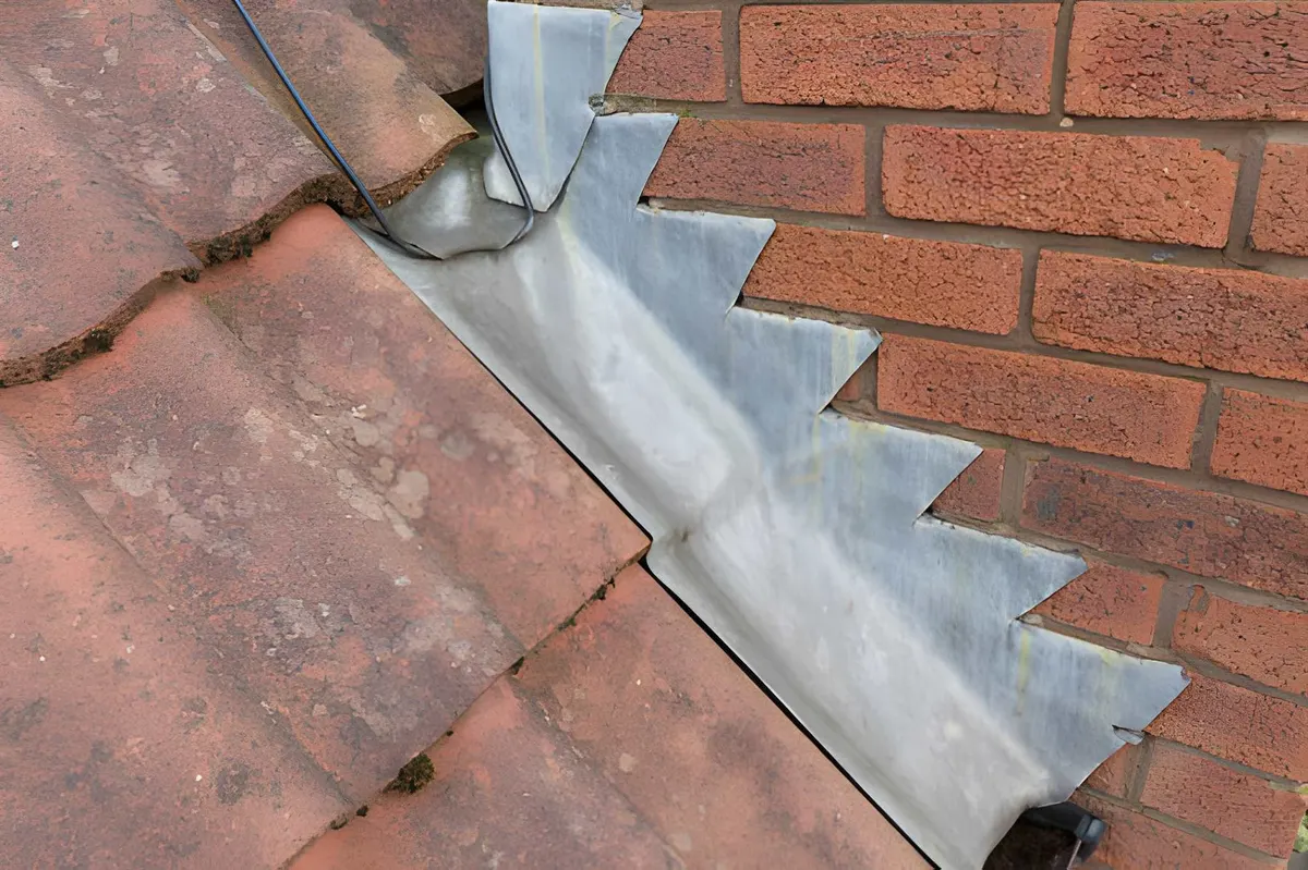 Lead flashing set into a tiled roof beside brickwork